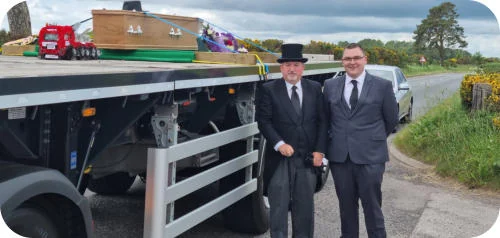 Two members of the Stonehaven Funeral Directors team beside the hearse lorry