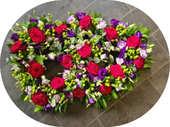 A heart-shaped floral tribute of red roses and mixed flowers