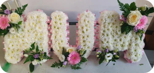 A floral tribute spelling MUM in white chrysanthemums with pink and cream roses